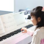 楽譜をみてピアノを弾く女の子